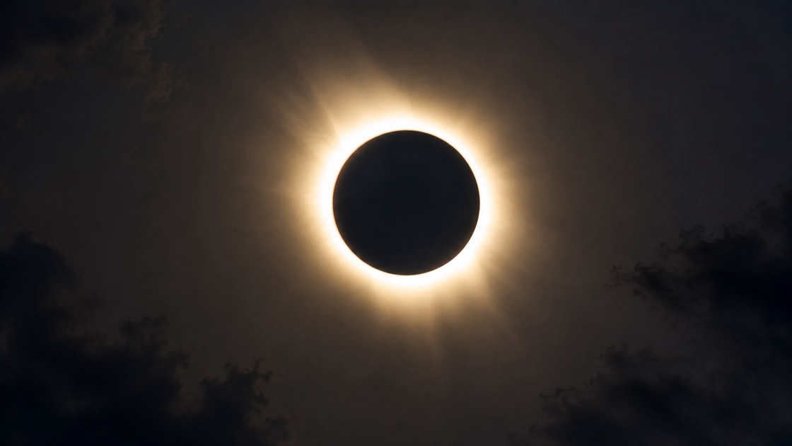 Eclipse total de Sol rodeado por la corona solar entre las nubes
