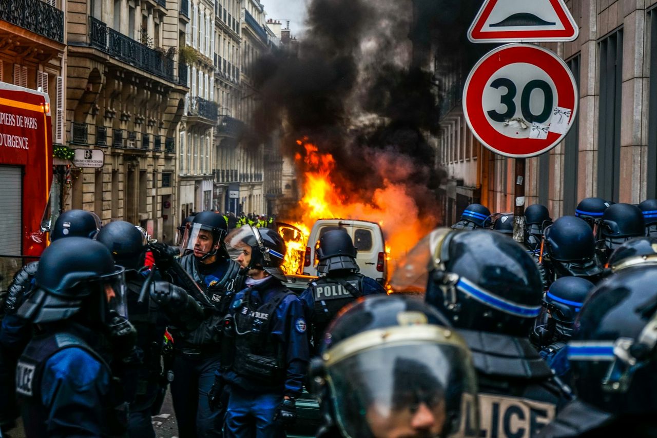 Policía antidisturbios ante un vehículo en llamas en una calle de París