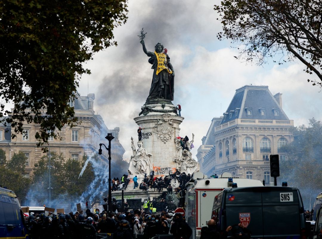 Manifestantes subidos al monumento de la plaza de la República de París entre gases lacrimógenos y furgones de la policía